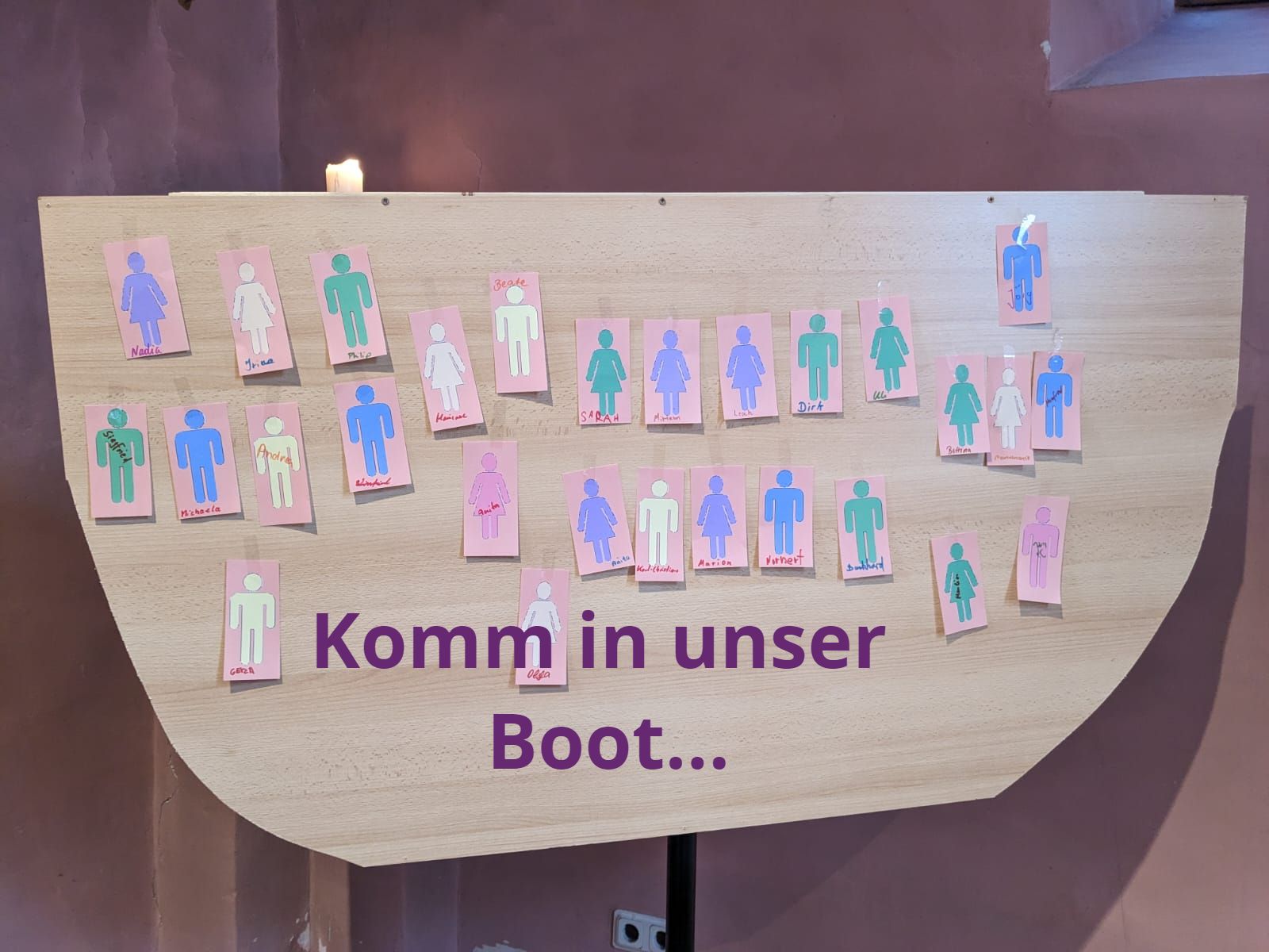 Figuren in einem Boot, Aufschrift: Komm in unser Boot...
